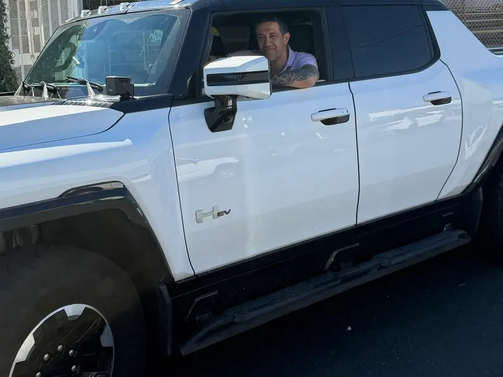 Closer view of the PG Auto Glass owner at the driver's window of a customer's white GMC HUMMER EV